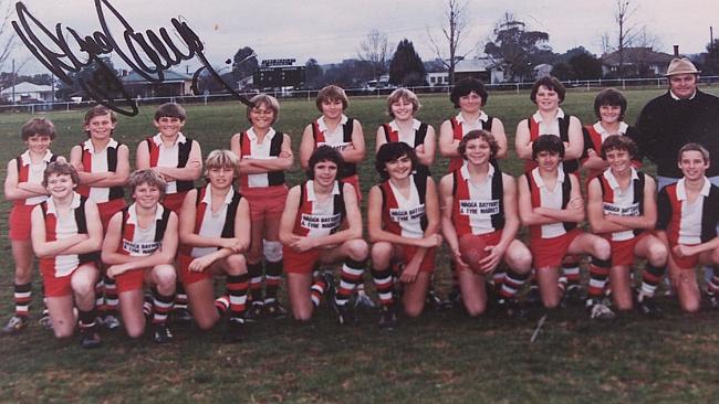 Wayne Carey: second from left, back row. Note scoreboard in the background. Image sourced from Herald Sun